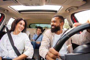 Car travel. Happy man and woman with fastened safety seat belts, looking at each other and smiling...