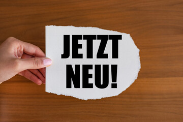 Jetzt neu! (Now new!) Woman hand holds a piece of paper with a note. Launch event, modern,...