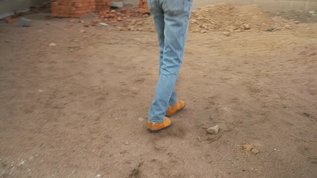 An unrecognizable construction worker in an orange vest dances at the site, moving with carefree energy and spontaneous joy. Letting go of routine, he enjoys a brief escape from the workday.