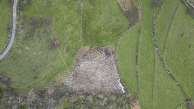 Aerial view of verdant fields stitched with stark brown patches under a web of power lines, Posof, Ardahan, T&Atilde;&frac14;rkiye.