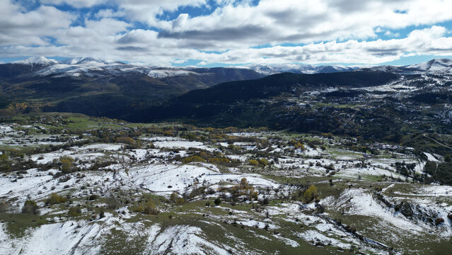 Aerial view of snow-dusted fields and forests meet distant, snow-capped mountains under a vast, cloud-strewn sky, Posof, Ardahan, T&Atilde;&frac14;rkiye.