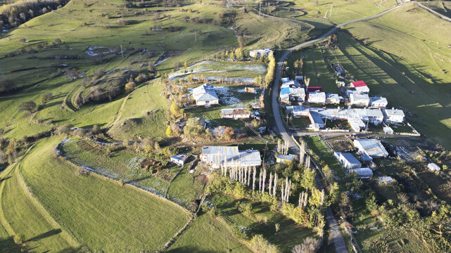 Aerial view of a village nestled amid rolling green hills, touched by early winter's frost, Posof, Ardahan, T&Atilde;&frac14;rkiye.