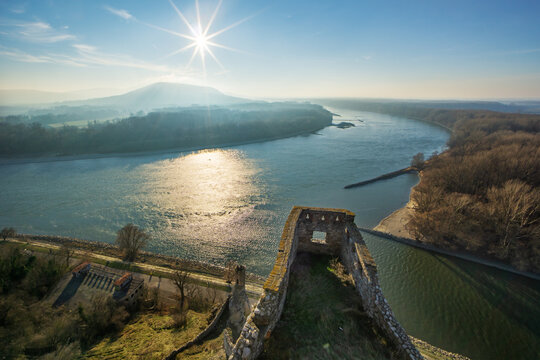Aerial view of ancient castle ruins meet the flowing river, framed by the landscape under the sun's radiant glow, Devin, Bratislava Region, Slovakia.