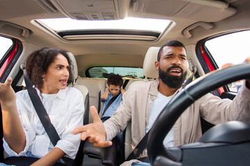 Latin parents arguing while driving car, kid boy feeling sad upset and covering ears with hands...