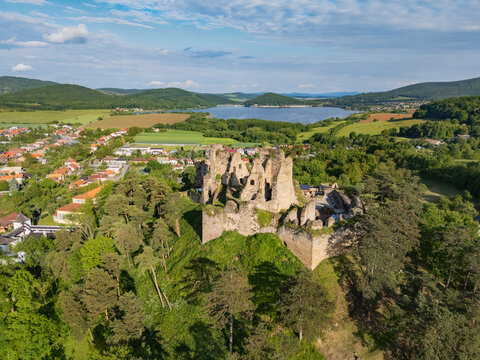 Aerial view of the weathered stone ruins of Divin Castle stand proudly atop a hill, overlooking the tranquil lake and verdant landscape, Div&Atilde;&shy;n, Bansk&Atilde;&iexcl; Bystrica Region, Slovakia.