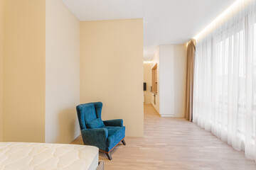 Cozy interior of a modern living space featuring a blue armchair and spacious kitchen area