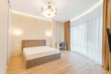 Modern bedroom with wooden floor, large windows, and elegant lighting during daylight hours