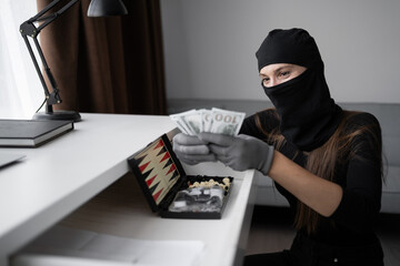 Burglar, robber or thief breaks home. Woman wearing black balaclava stealing money cash from house...