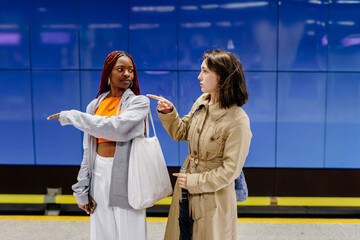 Two women pointing in different directions on metro platform
