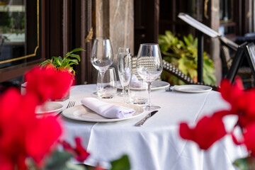 Elegant restaurant table for two with a white tablecloth and fine wine glassware, white crockery.