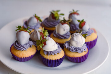 cupcakes con crema y frutilla en una mesa de madera.