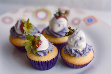 cupcakes con crema y frutilla en una mesa de madera.