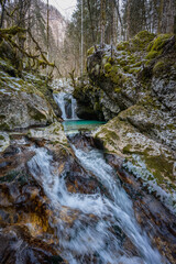 Small cascading waterfall in mossy alpine canyon with turquoise pool