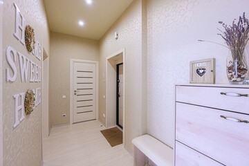 warmly lit hallway featuring doors, a dresser with decor, and wall art