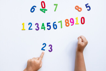 Child learning numbers with colorful wooden numerals on white background