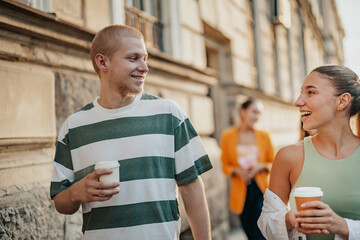 Students enjoy a sunny day outdoors while engaging in conversations and sipping coffee at their...