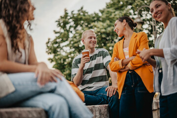 Group of university students enjoying their time outdoors while chatting and laughing in the park...