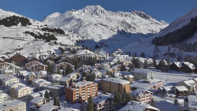 Andermatt, Switzerland in Winter. Aerial of mountain village in Swiss alps in Canton Uri on sunny day after snow fall. 