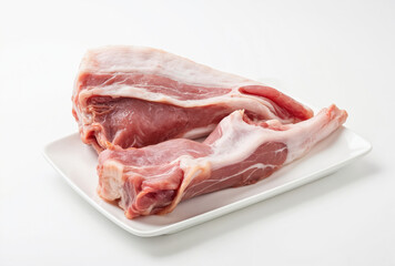 Fresh raw pork tail on white plate against white background. Healthy uncooked pig meat fillet, protein source. Butcher shop product. Macro detailed shot. Food photography concept. Restaurant serving