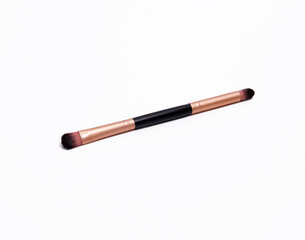 Dual-ended makeup brush with rose gold ferrules and brown bristles, used for blending eyeshadow