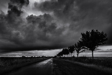 

WEATHER - Dramatic black rain clouds over fields and country road
