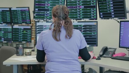A woman with her back turned, working in the IT room of a health center. - Powered by Adobe