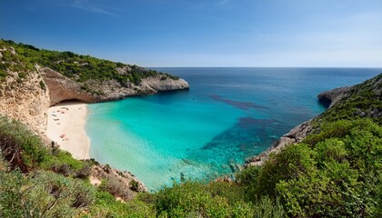 high angle view of a secluded cove with turquoise water lapping a sandy beach flanked by rocky cliffs and lush vegetation