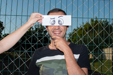 Portrait of a man with a funny drawn paper eyes	