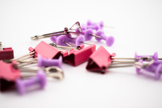 Red binder clips and purple push pins scattered on a white surface. A colorful flatlay of office supplies perfect for presentations, stationery themes, blogs, or productivity visuals.