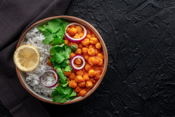 Chana masala, chickpea curry, traditional Indian dish, overhead flat lay shot with a place for text on a black background