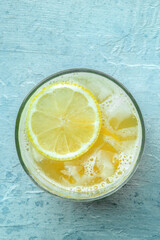 A glass of fresh lemonade, a mocktail with lemon juice, shot from the top on a blue background