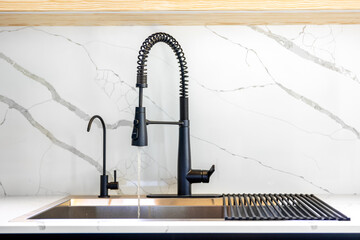 Running water stream. Black faucet. Marble wall