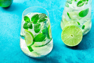 Lime lemonade, or limeade, in a glass with lime, mint, and ice. Fresh summer Mojito mocktail or cocktail, with ingredients, a close-up