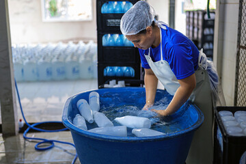 Asian fat female worker cleaning plastic water bottles outside and checking the quality of plastic...