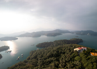 Aerial view of a serene lake surrounded by lush green islands and mountains under a cloudy sky. A...