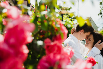Young married couple shares a tender moment in a colorful garden filled with blooming flowers and...