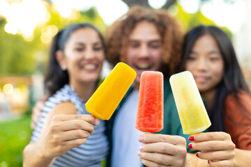 Happy friends showing colorful ice cream popsicles outdoors
