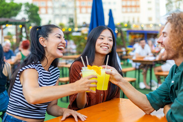 Happy friends toasting non alcoholic drinks at open air bar