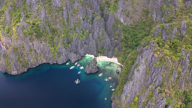 Bird's-eye survey of the beautiful Secret Lagoon and Jiji's Beach with boats, Miniloc Island, Philippines