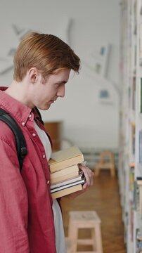 Redhead student looks for textbooks on shelves in library