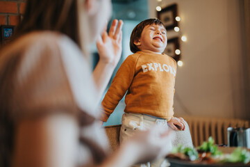 A cheerful child grinning brightly while enjoying quality time with a family member in a warm and welcoming home environment. The scene captures the lively bond and carefree happiness of family life.