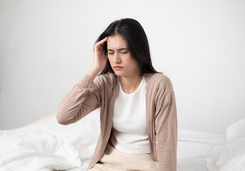 A woman holds her head with both hands because she is stressed or has a headache from lack of sleep...