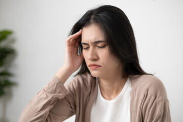 A woman holds her head with both hands because she is stressed or has a headache from lack of sleep...
