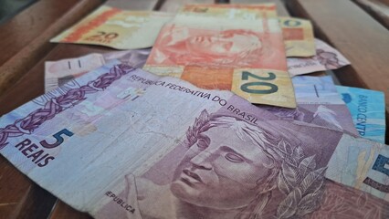 Brazilian real notes superimposed on a wooden background