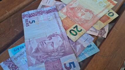 Brazilian real notes superimposed on a wooden background