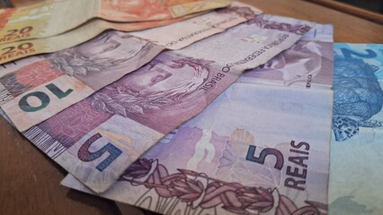 Brazilian real notes superimposed on a wooden background