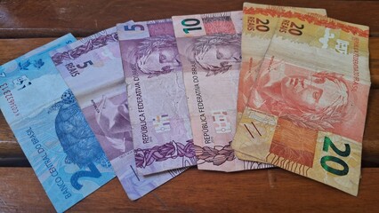 Brazilian real notes superimposed on a wooden background