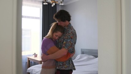 In the bedroom, a young couple snuggles, holding each other close. The man kisses the woman on the top of her head as she closes her eyes, finding comfort in his embrace while battling depression. - Powered by Adobe