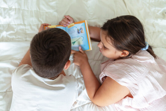 Children, reading and siblings in home with book for story time, education and literature adventure for storytelling. Boy, girl and together on bed for fantasy or bonding, learning and development.