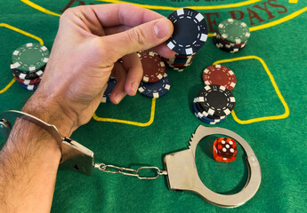 hands in handcuffs holding playing chips on a colored background